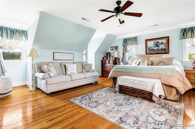 bedroom featuring ceiling fan, baseboards, wood finished floors, visible vents, and ornamental molding