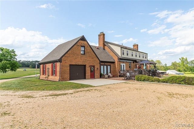 view of front of house featuring a gazebo, a front lawn, brick siding, a garage, and driveway