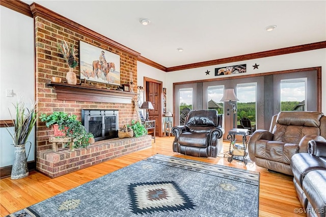 living room featuring ornamental molding, a brick fireplace, and wood finished floors