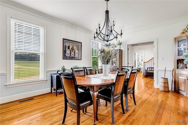 dining area with visible vents, crown molding, a notable chandelier, and light wood-type flooring