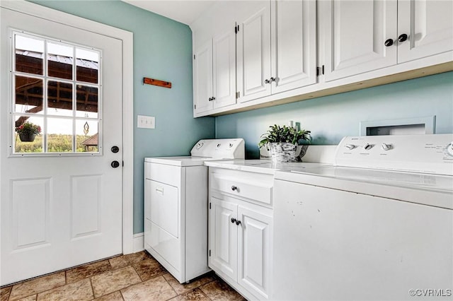 washroom with cabinet space, stone finish flooring, and washing machine and dryer