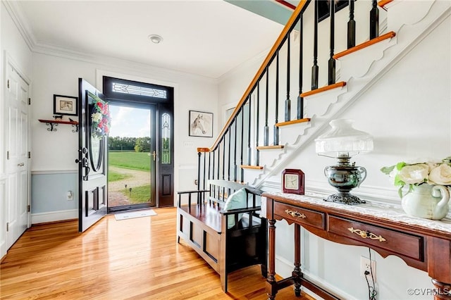entrance foyer featuring crown molding, light wood-style flooring, stairs, and baseboards