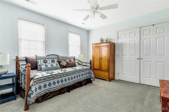 bedroom with a ceiling fan, light colored carpet, visible vents, and a closet
