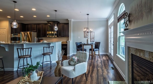 kitchen with stainless steel appliances, a breakfast bar area, dark wood finished floors, crown molding, and recessed lighting