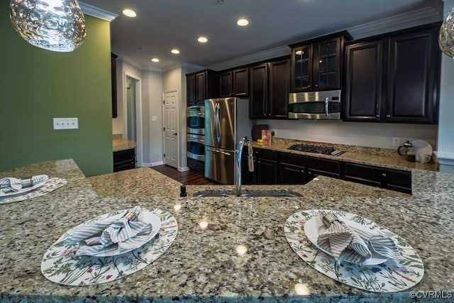 kitchen featuring appliances with stainless steel finishes, a sink, crown molding, recessed lighting, and light stone countertops