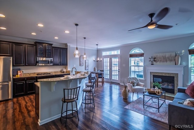kitchen with appliances with stainless steel finishes, a kitchen bar, plenty of natural light, open floor plan, and crown molding