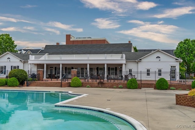 rear view of house featuring fence, an outdoor pool, and a patio area