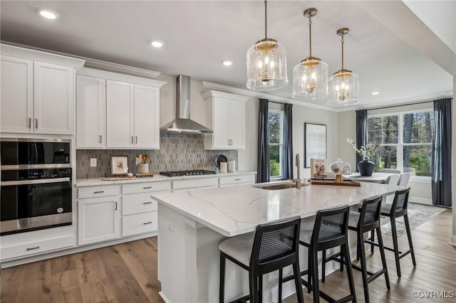 2710 Maidens Rd, Powhatan, VA 23139 - kitchen featuring appliances with stainless steel finishes, tasteful backsplash, light stone countertops, a sink, and wall chimney exhaust hood