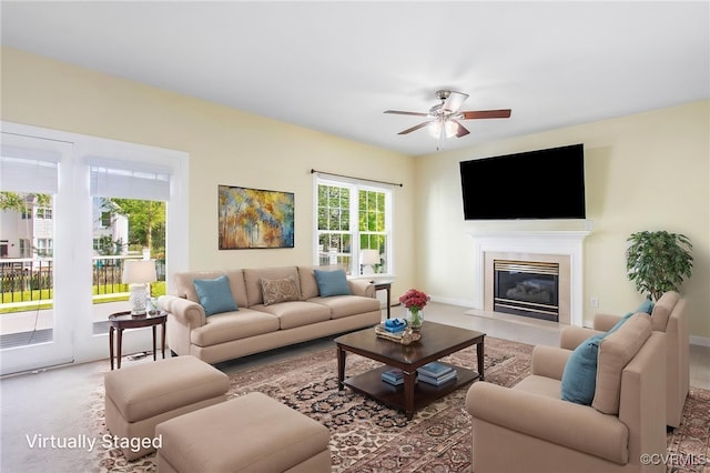living room featuring a fireplace with flush hearth and ceiling fan