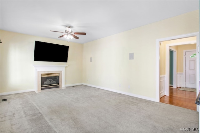 unfurnished living room with a fireplace with flush hearth, baseboards, ceiling fan, and carpet