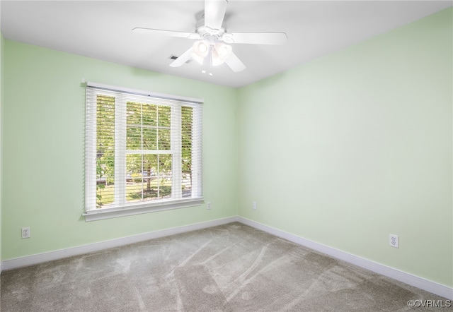 empty room with carpet flooring, a ceiling fan, and baseboards