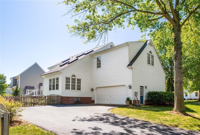 exterior space with fence, an attached garage, a lawn, and driveway