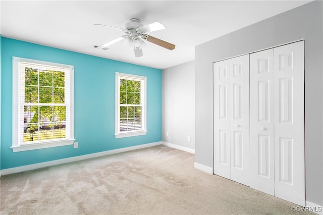 unfurnished bedroom featuring carpet floors, baseboards, ceiling fan, and a closet