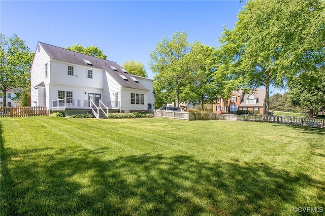 rear view of property with a lawn, fence, and a deck