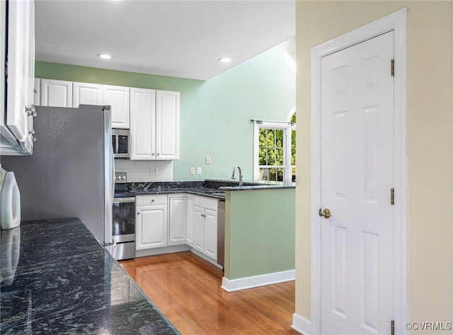 kitchen featuring a sink, appliances with stainless steel finishes, light wood-style floors, and white cabinetry