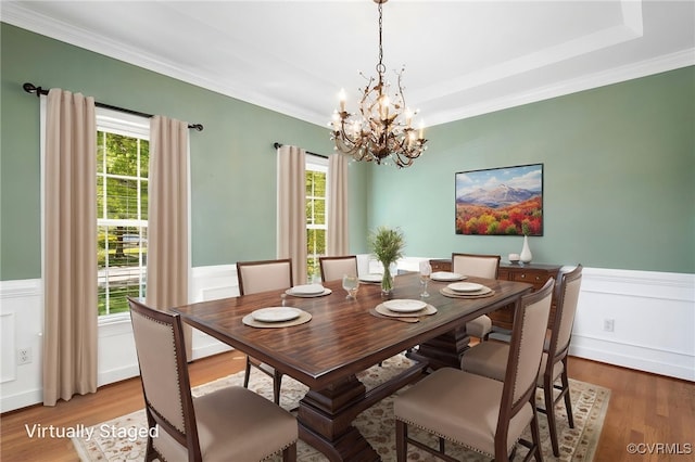 dining room with an inviting chandelier, a wainscoted wall, ornamental molding, and wood finished floors