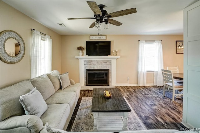 living room with plenty of natural light, wood finished floors, ceiling fan, and a brick fireplace