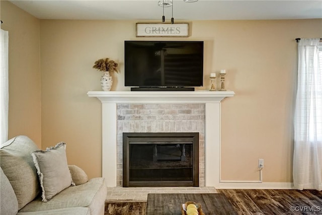 living room with wood finished floors, baseboards, and a brick fireplace