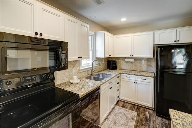 kitchen with black appliances, a sink, white cabinets, light stone countertops, and backsplash