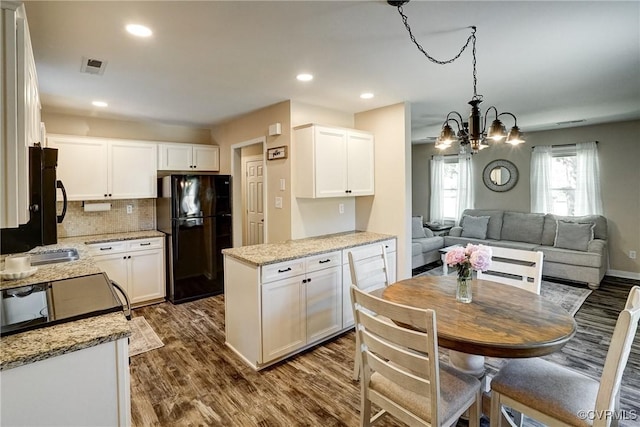 kitchen featuring freestanding refrigerator, white cabinets, a chandelier, dark wood-type flooring, and recessed lighting