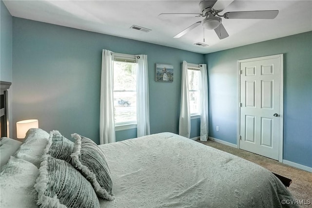 carpeted bedroom featuring baseboards, multiple windows, and a ceiling fan