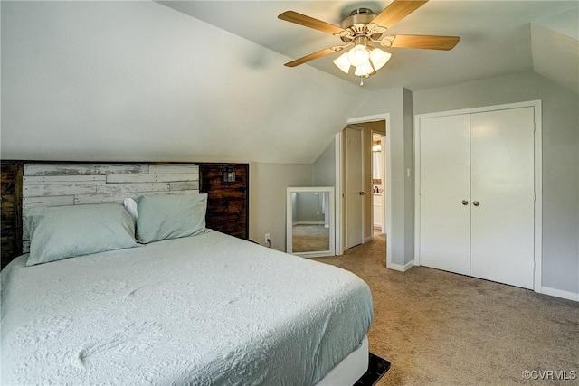 bedroom with vaulted ceiling, light colored carpet, a ceiling fan, baseboards, and a closet
