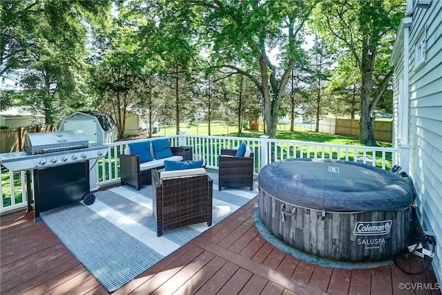 wooden deck featuring outdoor lounge area, a hot tub, a fenced backyard, grilling area, and a shed