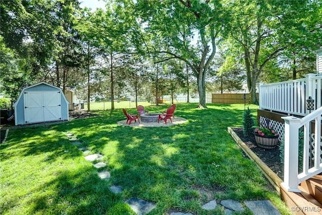 view of yard with a fire pit, a shed, an outdoor structure, and view of wooded area