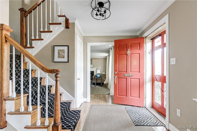 entryway featuring crown molding, baseboards, stairs, and wood finished floors