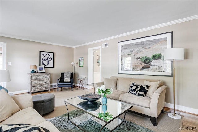 living room with crown molding, baseboards, wood finished floors, and visible vents