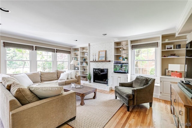 living room featuring crown molding, a fireplace, a healthy amount of sunlight, and light wood-style floors