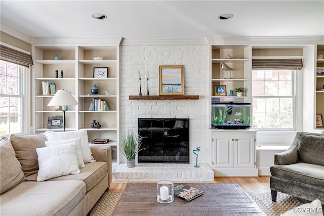 living area with plenty of natural light, built in features, light wood finished floors, and a fireplace