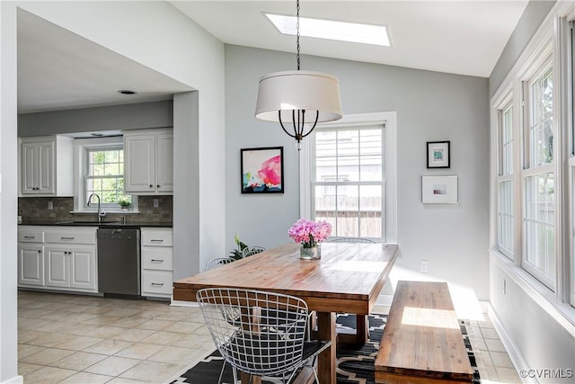 dining room featuring baseboards, light tile patterned floors, and vaulted ceiling with skylight