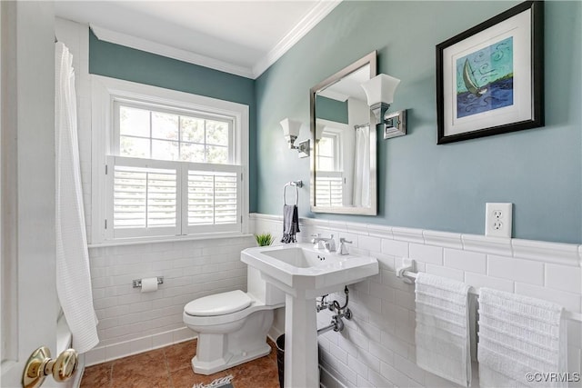 bathroom featuring crown molding, toilet, tile patterned floors, a wainscoted wall, and tile walls