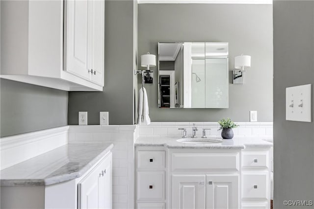 bathroom with vanity, a wainscoted wall, and tile walls
