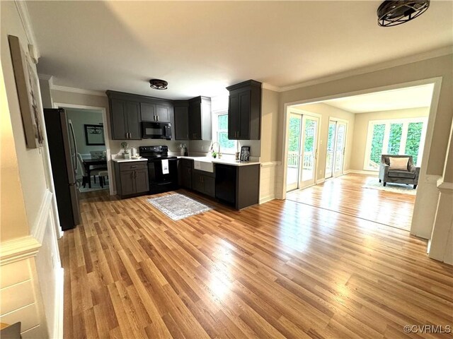 kitchen featuring black appliances, crown molding, a sink, light countertops, and light wood finished floors