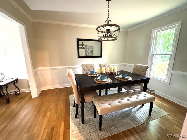 dining space featuring a chandelier, wood finished floors, baseboards, and crown molding