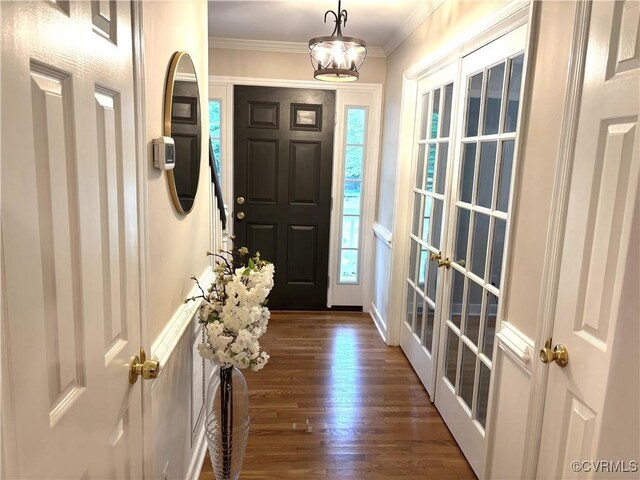 foyer with dark wood finished floors, crown molding, healthy amount of natural light, and french doors