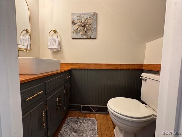 bathroom with wood finished floors, toilet, lofted ceiling, and vanity