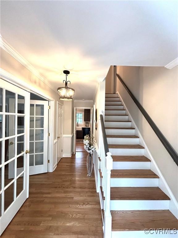 staircase featuring ornamental molding, wood finished floors, and french doors