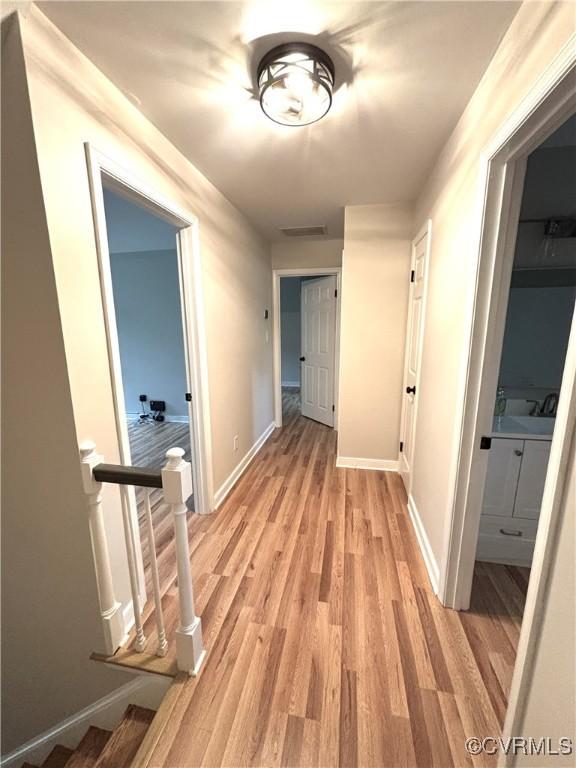 hallway featuring light wood finished floors and baseboards