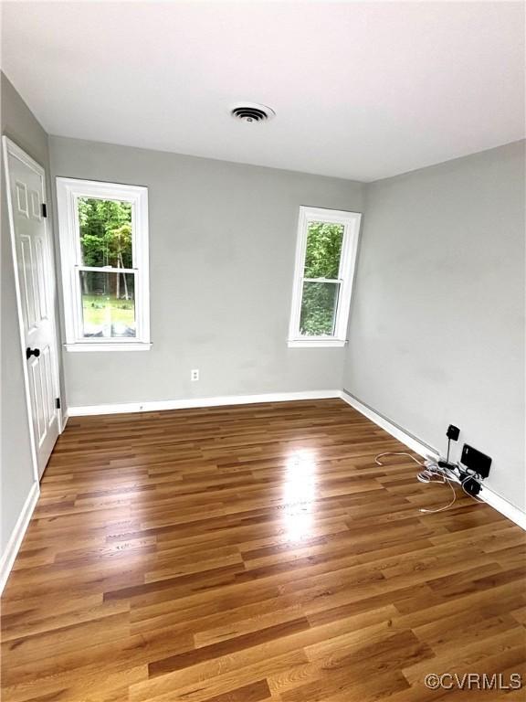 empty room with plenty of natural light, light wood-style flooring, and baseboards