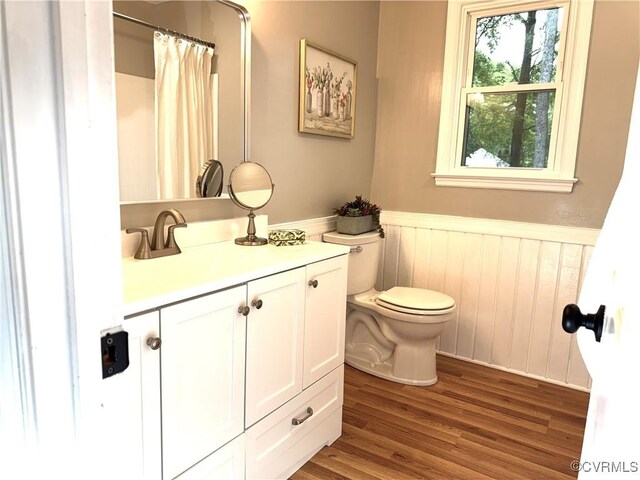 full bathroom with wainscoting, toilet, wood finished floors, vanity, and curtained shower