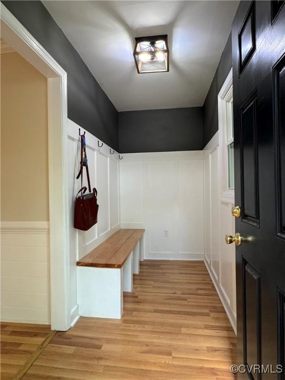 mudroom with light wood finished floors and a wainscoted wall
