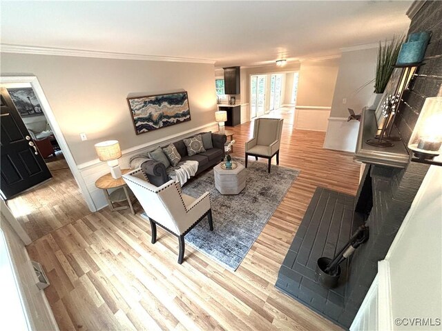 living room with crown molding, light wood-style flooring, and baseboards