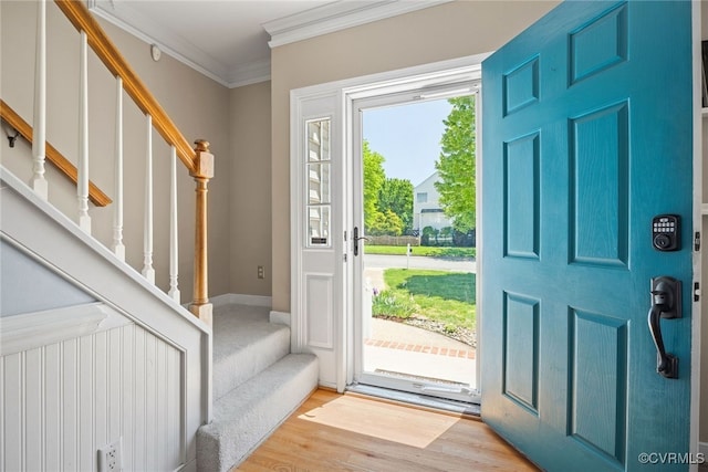 entrance foyer with ornamental molding, stairs, and wood finished floors