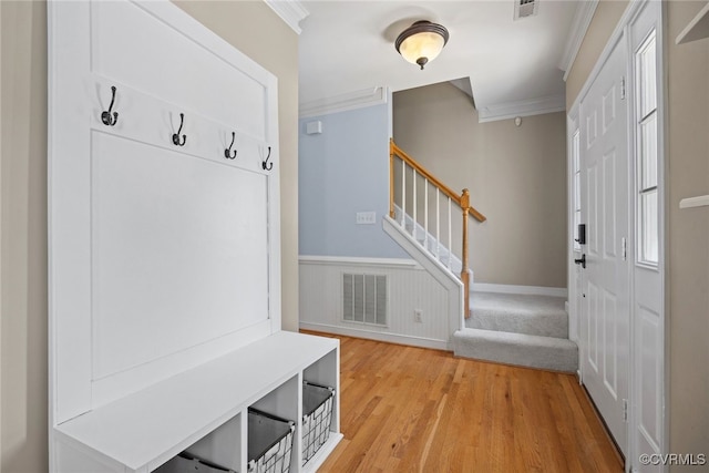 mudroom featuring visible vents, ornamental molding, light wood-style floors, and wainscoting