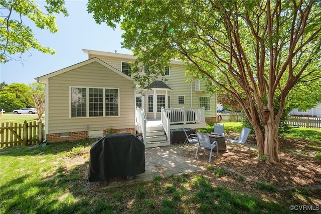 back of property featuring fence, a wooden deck, crawl space, a lawn, and a patio