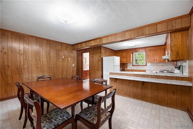 dining room featuring wooden walls and brick patterned floor