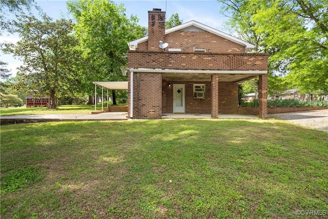 view of front of home with brick siding, a detached carport, a front yard, and a chimney